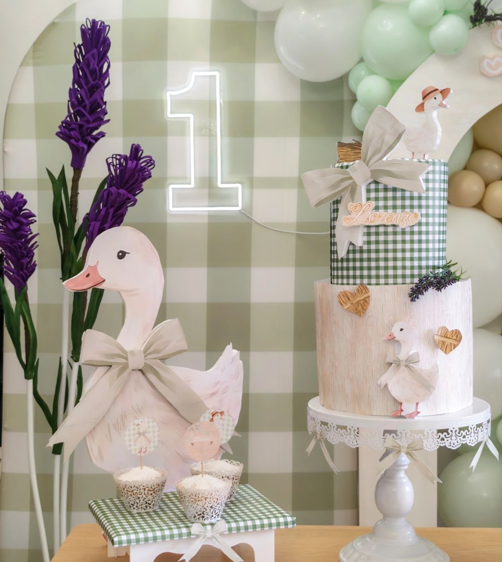 Dettaglio di oca, cupcake su alzatina decorata con carta vichy che riprende lo sfondo, sagoma di ochetta, torta scenografica a tema ochetta, in fondo dettaglio di fiore gigante di lavanda, allestimento realizzato da Alessia Vincenti a Roma tema ochette con semiarco di palloncini,